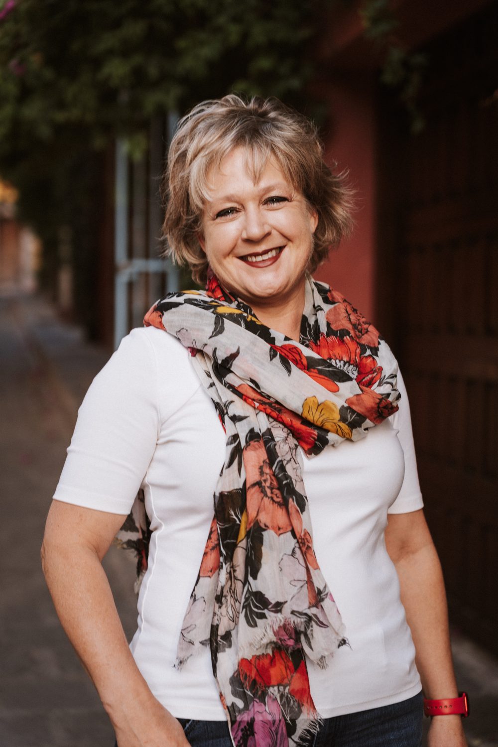 Chérie L. Hughes smiling on a street in San Miguel de Allende, wearing a floral scarf