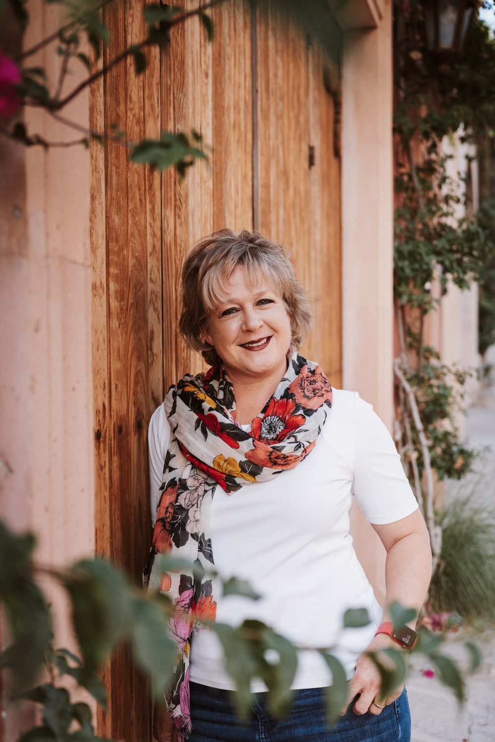 Chérie L. Hughes in front of a wooden door framed by greenery in San Miguel de Allende